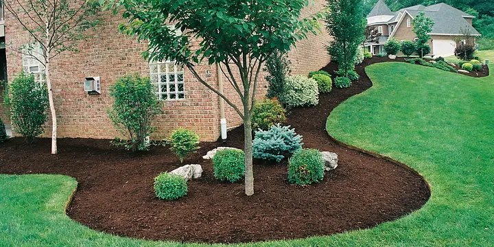 Manicured lawn with mulched landscape beds along a brick house